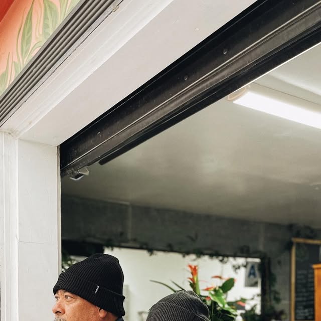 Two people holding drinks at Plantology Cafe outdoor window